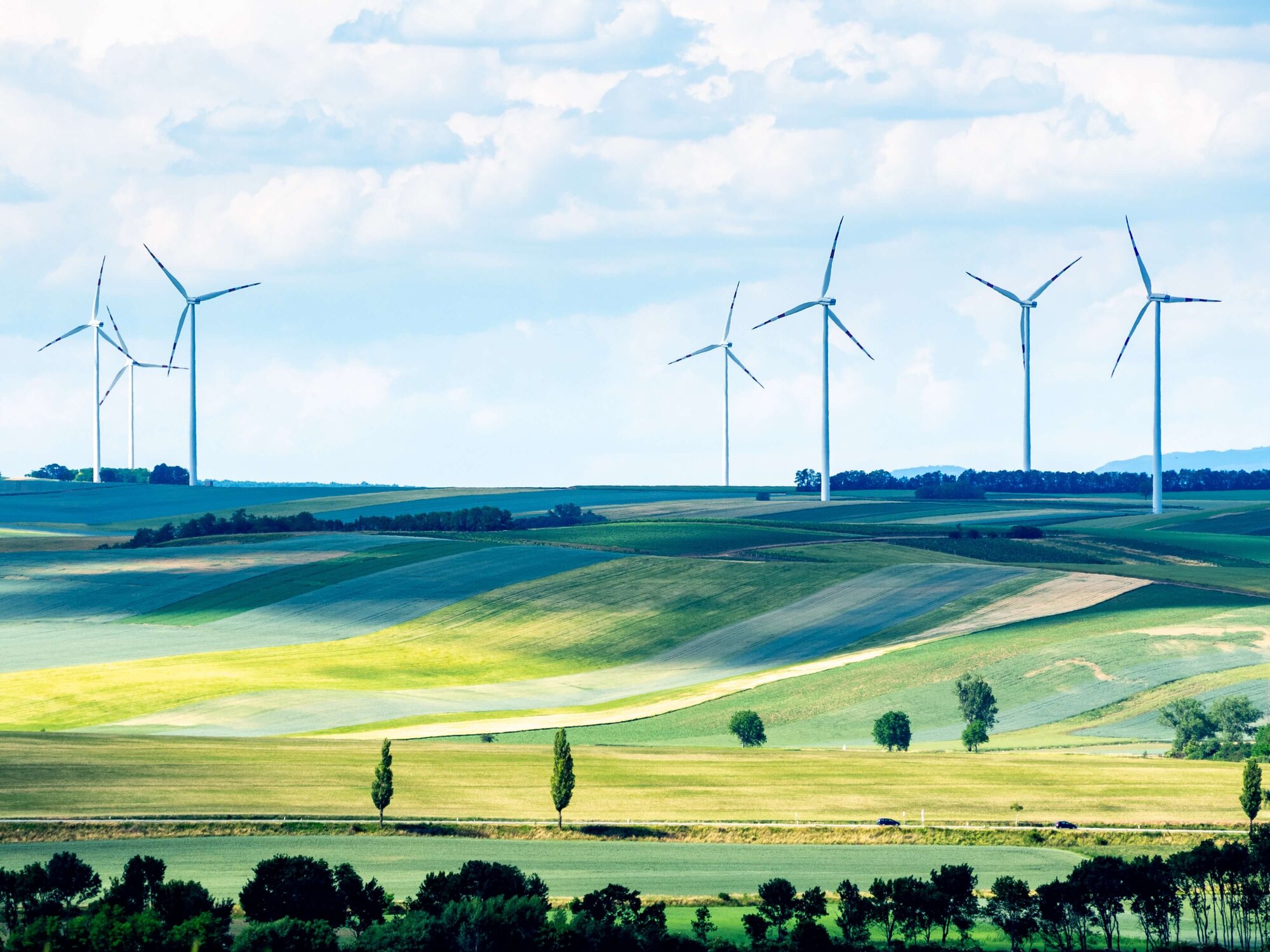 wind turbines on land with blue sky and green fields